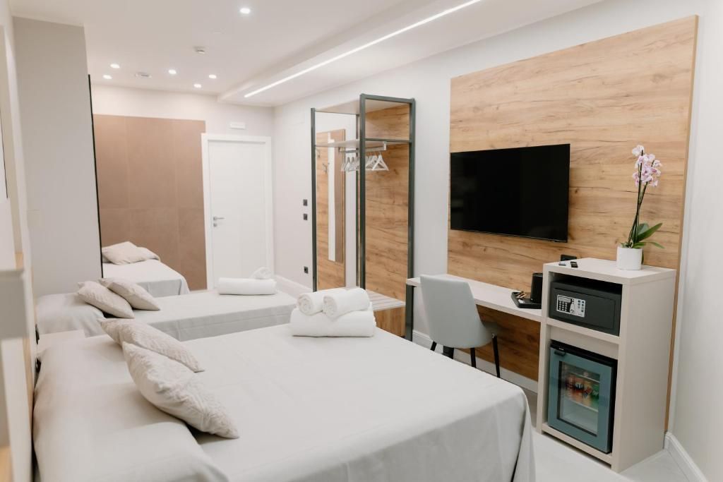 A hotel room with two beds, a desk with a computer, a TV, and a minibar.
