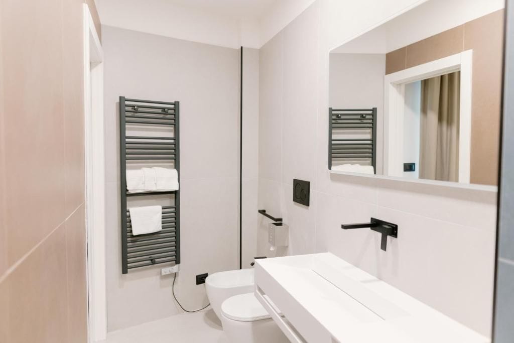 A modern bathroom with a toilet, a towel rack, and a mirror.