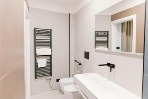 Un baño moderno con inodoro, toallero y espejo.
