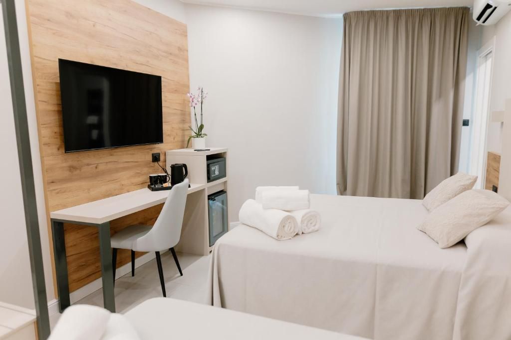 Une chambre d’hôtel équipée d’un lit, d’un bureau, d’une chaise, d’une télévision et d’une fenêtre avec des rideaux.
