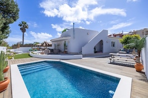 A modern poolside area with a clear blue pool, white walls, and a wooden deck. - Luxury Lagos Villa, with Seaview. Close to the Old Town and pristine beaches (Lagos)