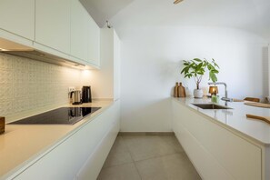 A modern kitchen with white cabinetry, a black countertop, and a single plant on the island. - Luxury Lagos Villa, with Seaview. Close to the Old Town and pristine beaches (Lagos)