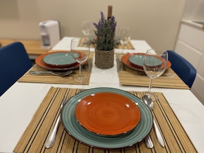 Een eettafel gedekt met borden, glazen, bestek en een middelpunt.