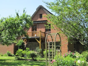 Ein Ziegelhaus mit einem Holzbalkon und einem Garten.