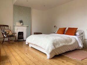Une chambre à coucher avec un lit, une chaise, une cheminée et une table de chevet.
