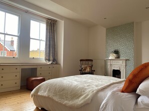 A bedroom with a large bed, a wooden desk, a chair, a fireplace, and a window with curtains. - Spacious 5-Bed Victorian Home with Garden near Richmond & London (Richmond)