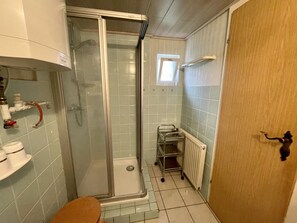 Ein Badezimmer mit einer Duschkabine, Toilette, Waschbecken mit Wasserhahn und einem Heizkörper.