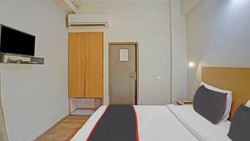 Ett hotellrum med en säng, en tv, en luftkonditioneringsanläggning och en garderob i trä.