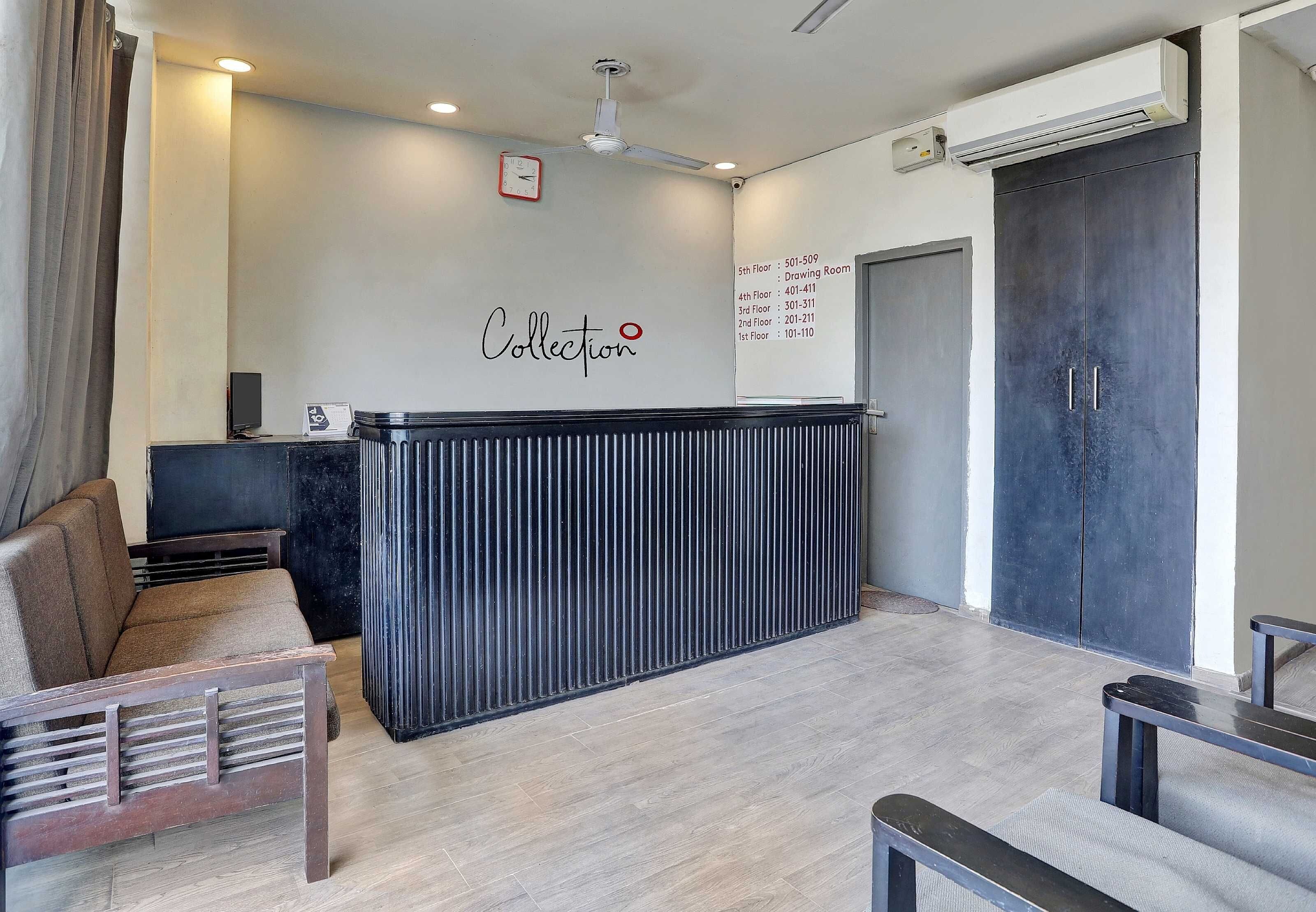 A reception area with a black reception desk, a clock, and a wall sign indicating floor numbers and room numbers.