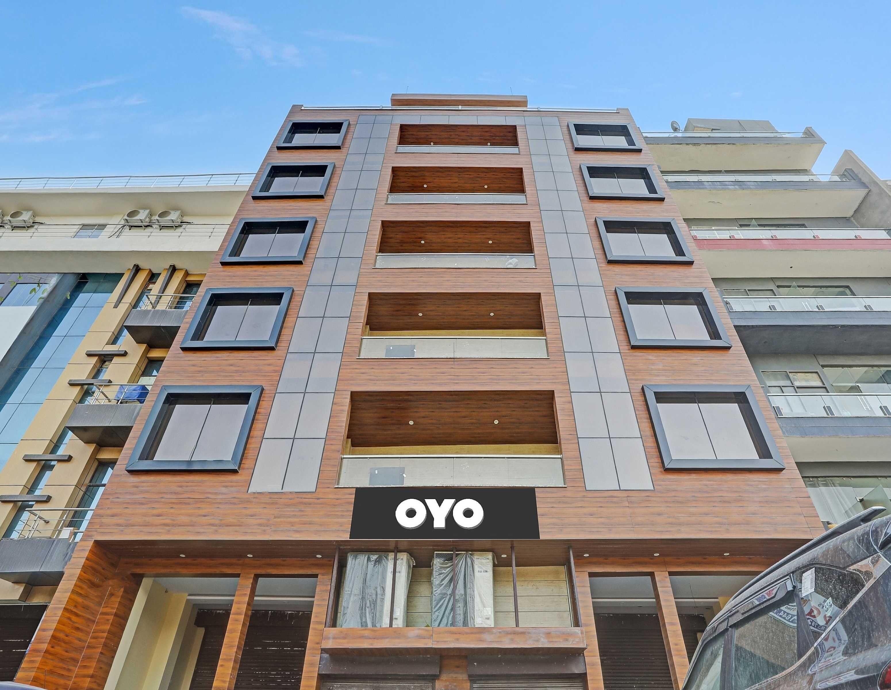 En flereetagers bygning med et tydeligt 'OYO'-skilt på facaden, med et moderne arkitektonisk design, der kombinerer træ og metal.