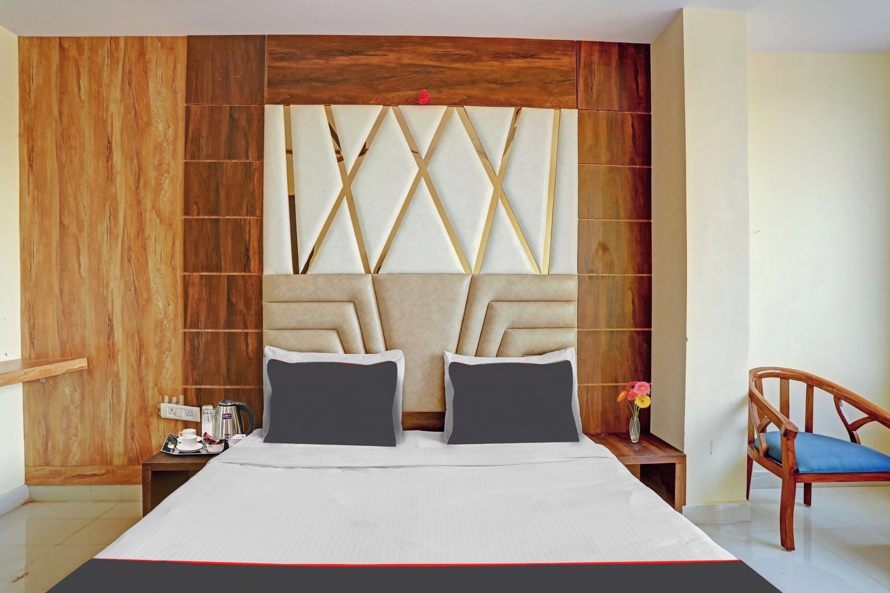 A hotel room with a large bed, two bedside tables, a wooden headboard, and a wooden chair.
