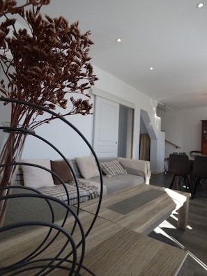 Ein modernes Wohnzimmer mit einer Couch, einem Couchtisch und einer Vase mit Trockenblumen.