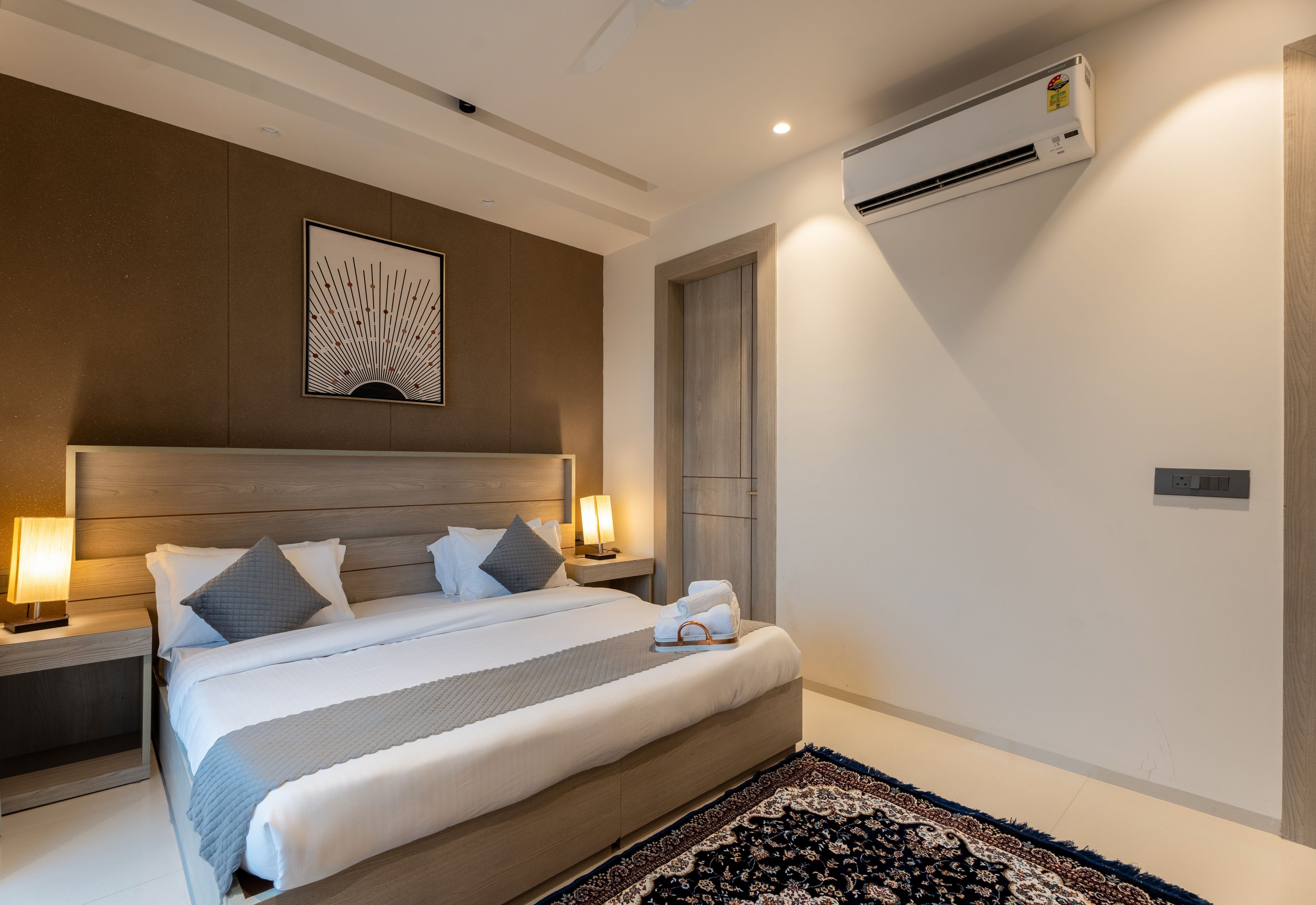Habitación de hotel con cama, mesitas de noche, aire acondicionado de pared y un adorno sobre la cama.