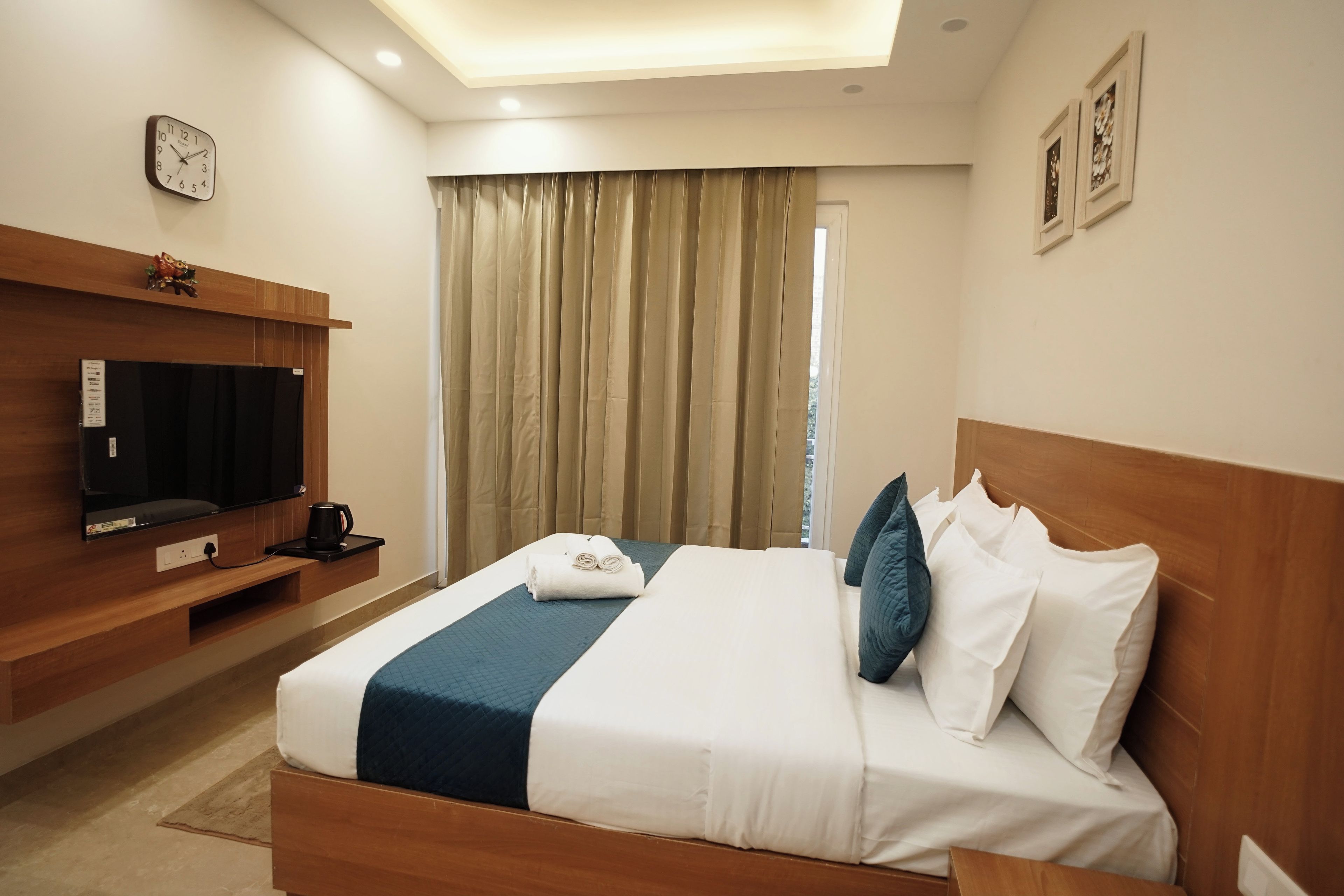 A hotel room with a bed, a television, a coffee maker, and a window with curtains.