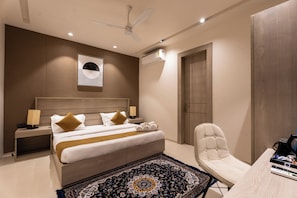 Habitación de hotel moderna con cama, mesitas de noche, escritorio, silla, ventilador de techo y aire acondicionado.