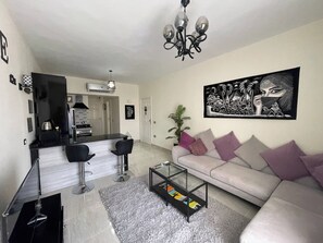 A modern living room with a sofa, coffee table, and bar area. - Sunshine & Smiles Nabqs Most Lovely Apartment (Sharm El Sheikh)