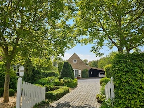 Ein Haus mit befestigter Auffahrt, die zu einer Garage führt, umgeben von gepflegten Hecken und Bäumen.