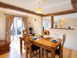 A dining area with a wooden table, chairs, a coffee pot, and a view of the outdoors. - Highbeck (Kendal)