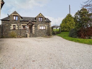A stone building with a gravel driveway and a wooden pergola. - High Beck Cottage (Kendal)