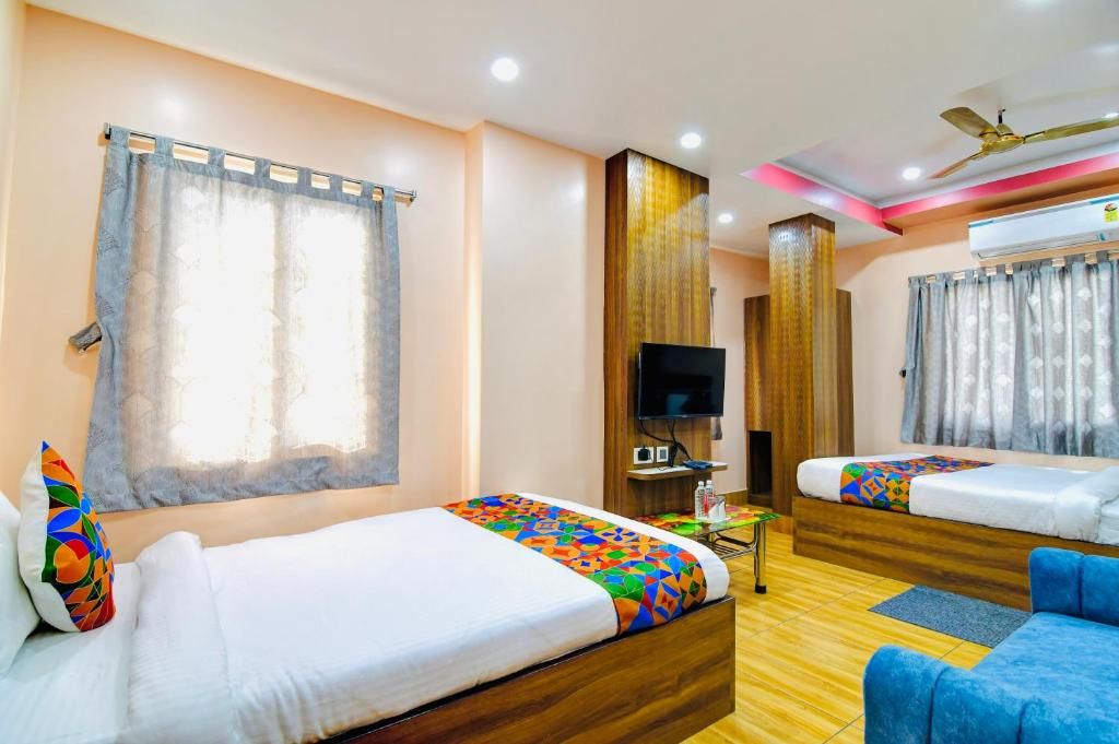 A hotel room with two beds, a TV, an air conditioning unit, and a ceiling fan.