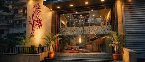 The exterior of Hotel Kanan Inn, featuring a well-lit entrance with a staircase, potted plants, and a visible signboard.