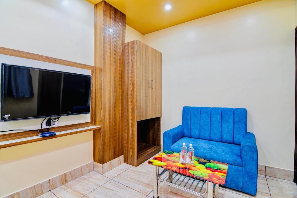 Una sala de estar con televisor de pantalla plana, un sofá azul, una mesa de centro con fruta y un mueble de madera.