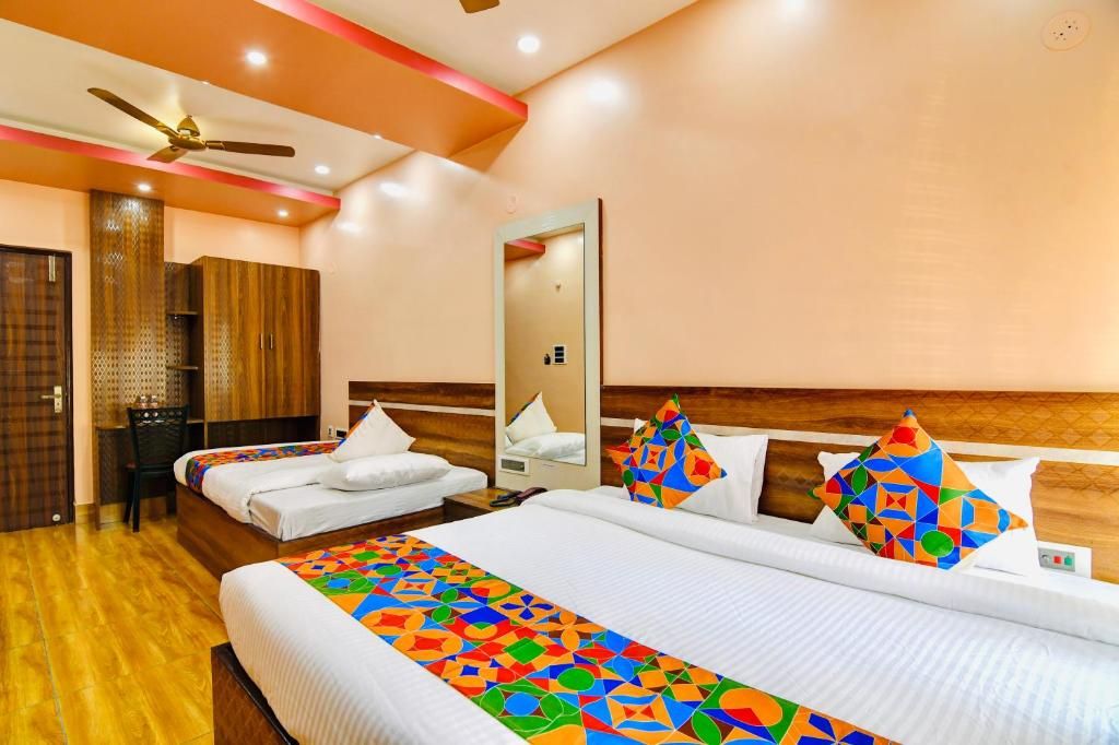 A hotel room with two beds, a mirror, a ceiling fan, and a wooden wardrobe.