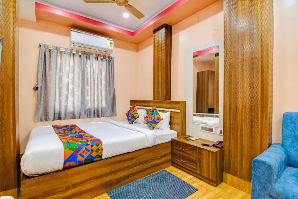 Habitación de hotel con una cama, una mesita de noche, un espejo y un ventilador de techo.