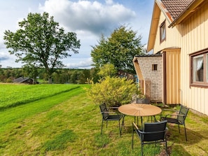 A house with a patio table and chairs, surrounded by a well-maintained lawn and trees. - Holiday Home in Hokerum With Swimming Pool (Hökerum)