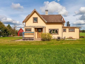 A two-story house with a front porch, a chimney, and a red barn in the background. - Holiday Home in Hokerum With Swimming Pool (Hökerum)