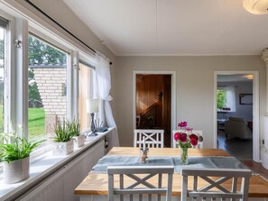 A dining area with a table and chairs, a window with plants, and a view of a wooden staircase leading to another room. - Holiday Home in Hokerum With Swimming Pool (Hökerum)