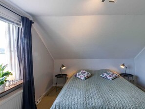 A bedroom with a bed, two bedside lamps, a window with curtains, and a radiator. - Holiday Home in Hokerum With Swimming Pool (Hökerum)