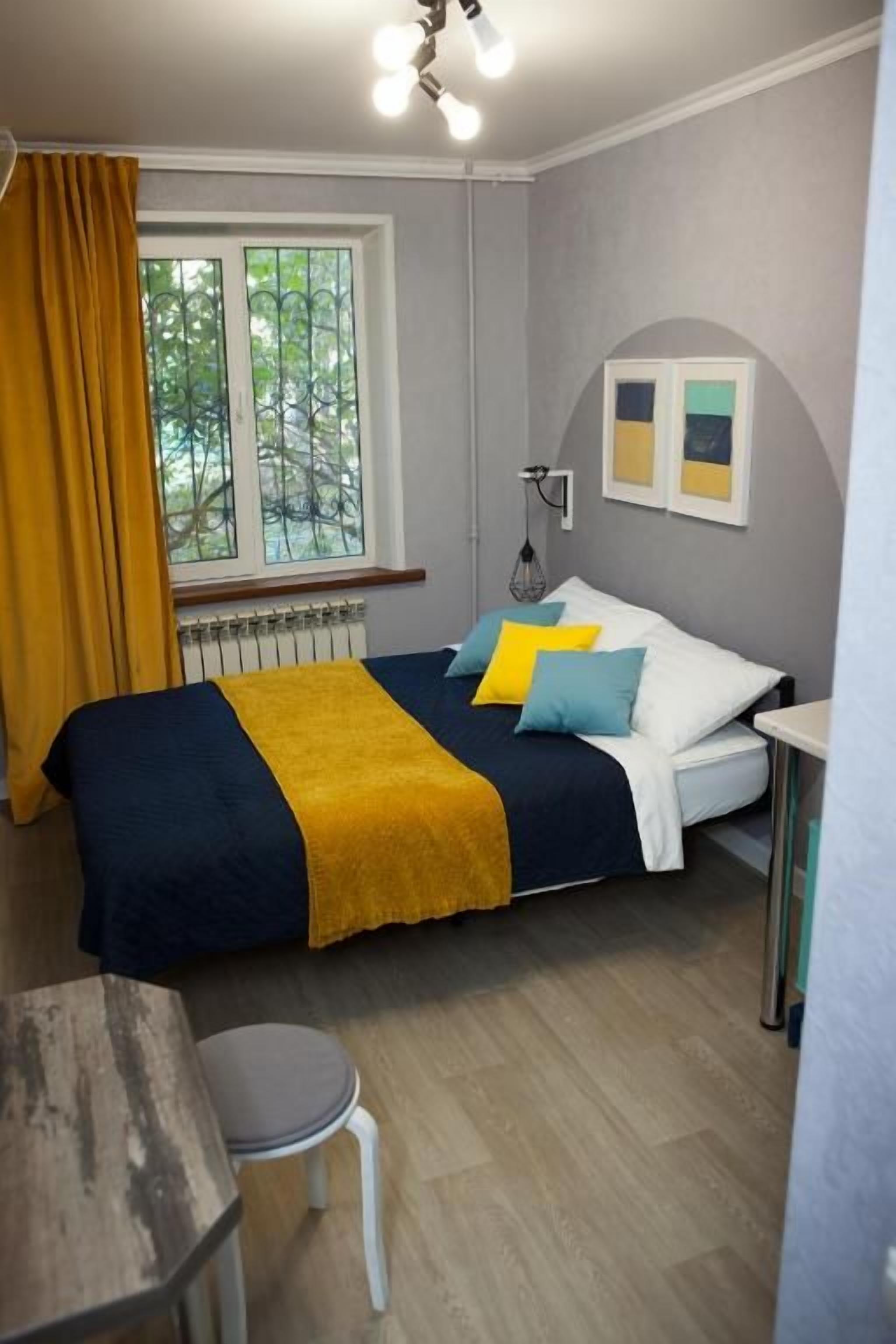 Une chambre à coucher avec un lit, une fenêtre avec des rideaux, un radiateur et une petite table.