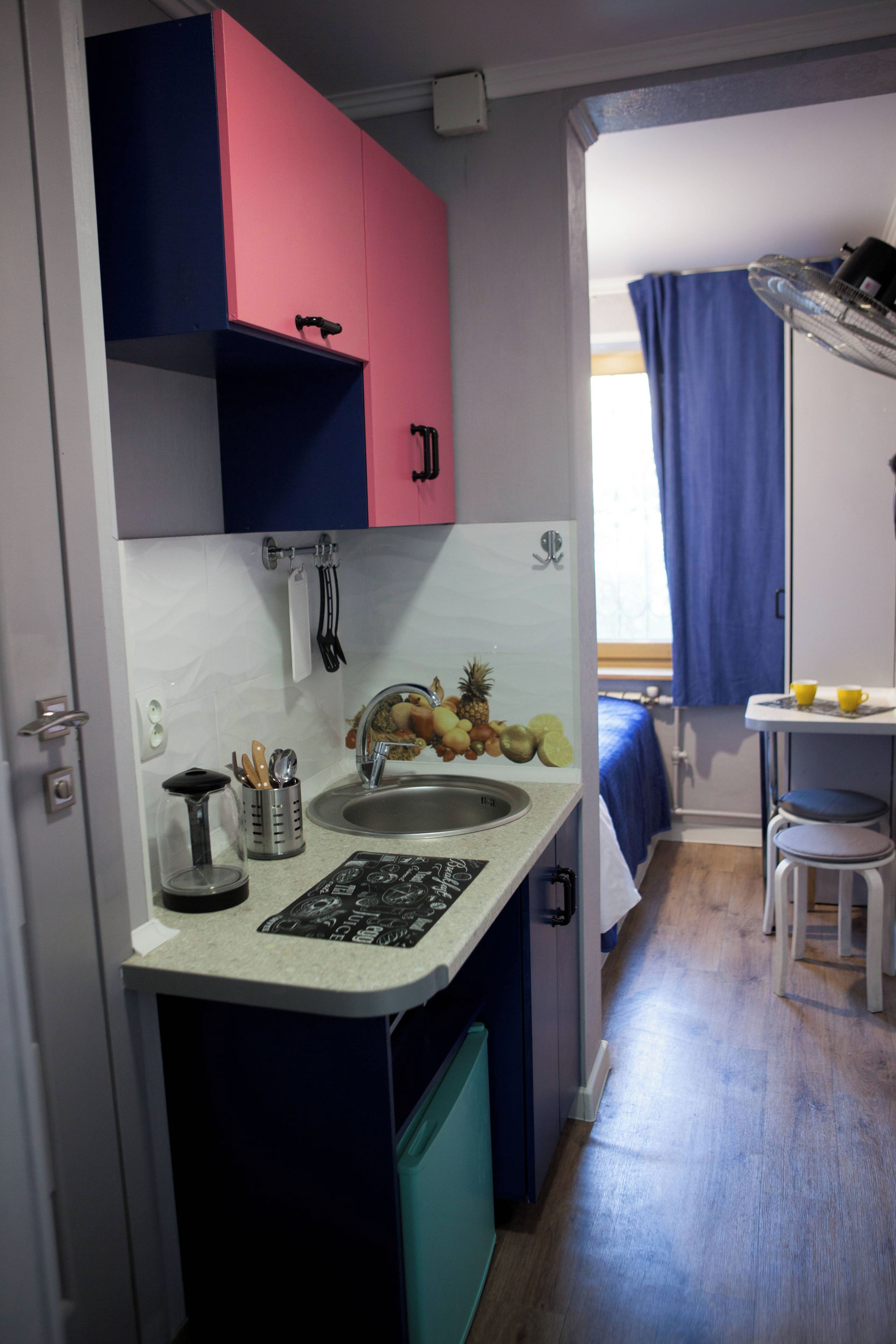 Una kitchenette compacta con un lavamanos, una pequeña encimera y una ventana con vistas al exterior.