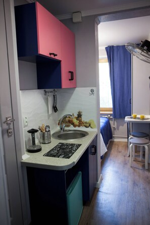 Una kitchenette compacta con un lavamanos, una pequeña encimera y una ventana con vistas al exterior.