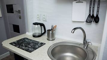 A kitchen with a stainless steel sink, a coffee maker, a knife holder, and a black and white placemat on the countertop.