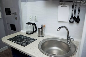 A kitchen with a stainless steel sink, a coffee maker, a knife holder, and a black and white placemat on the countertop. - AlmatyDa on Basenov Street (Almaty)