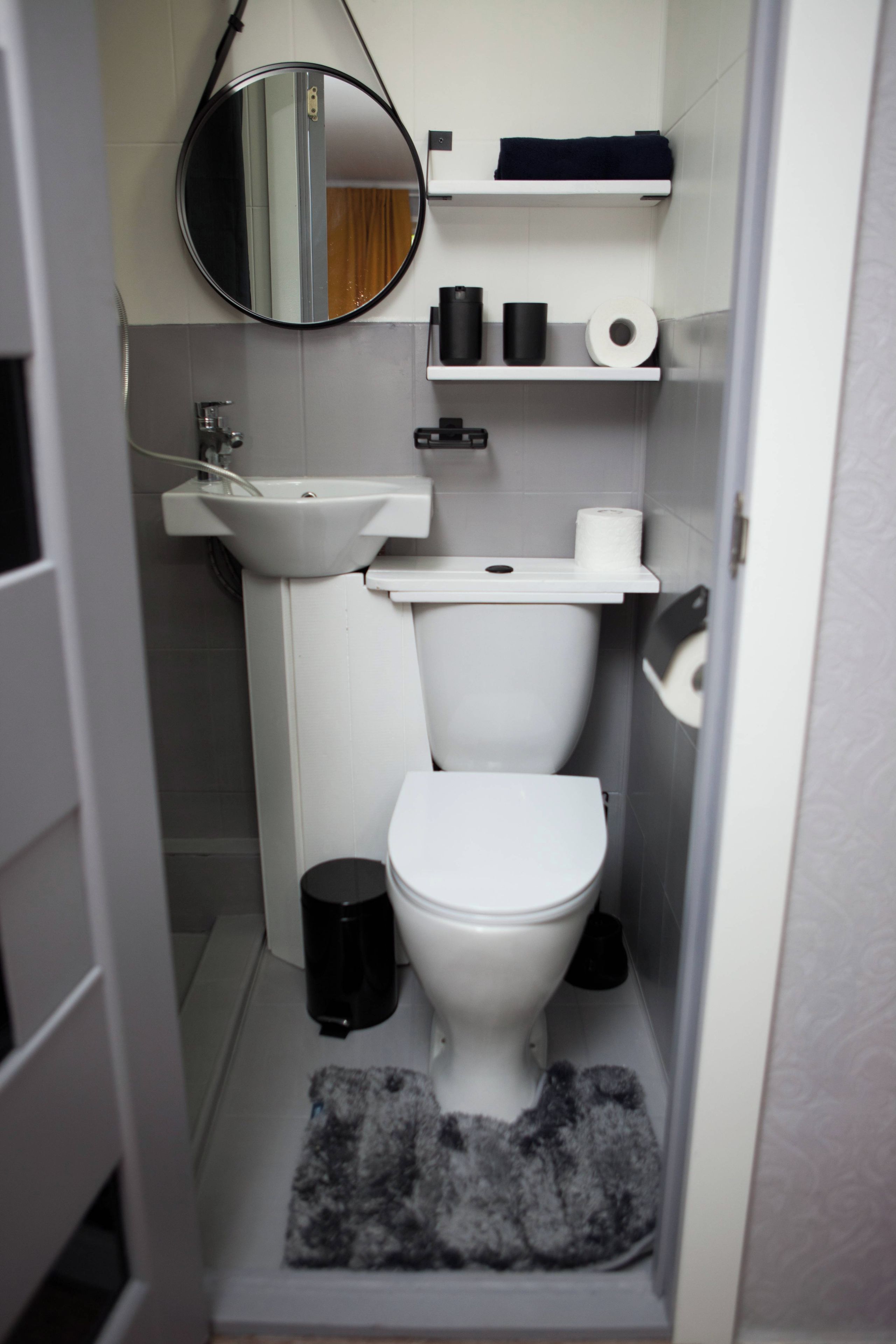 Un baño pequeño con inodoro, lavamanos y espejo.