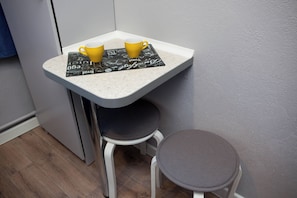 A small kitchen area with a white countertop, two yellow cups, and a black placemat with text.