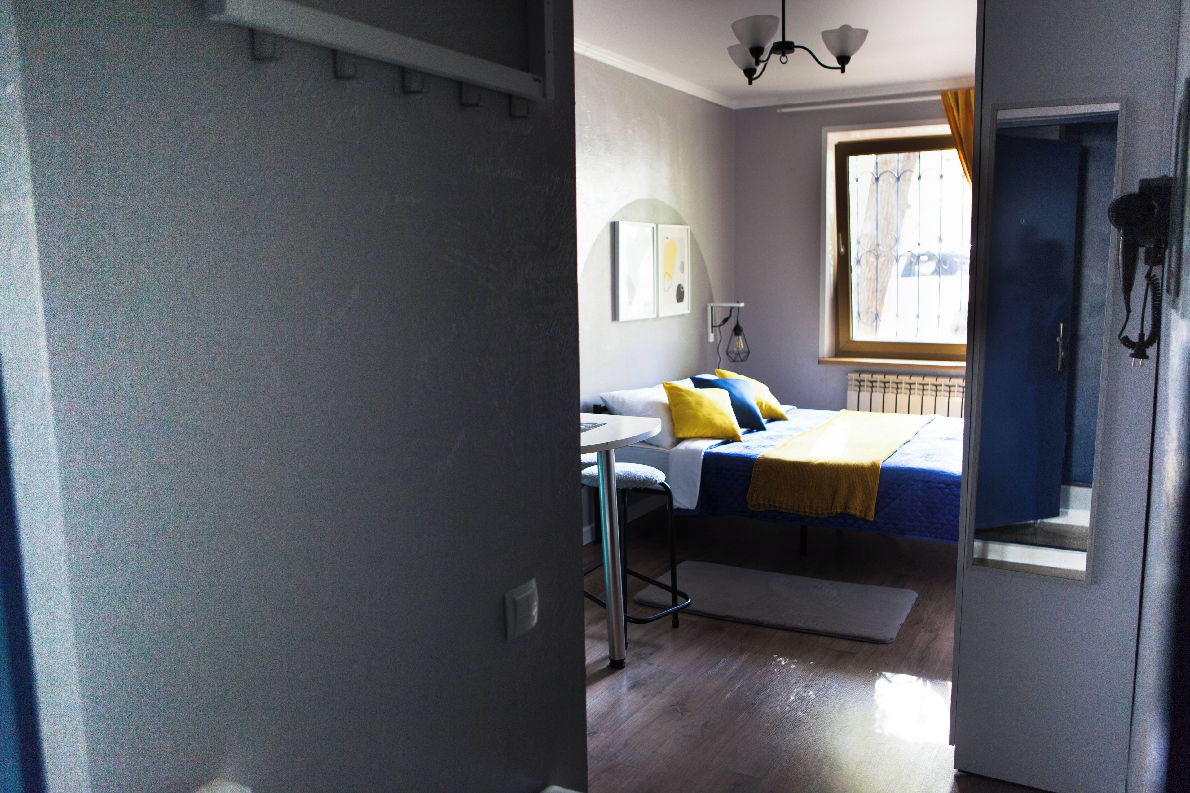 Una habitación con cama, escritorio, silla, ventana con cortinas y puerta.