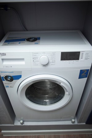 A front view of a white beko washing machine with a control panel and a transparent drum.
