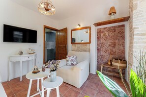 A living room with a flat-screen TV, a wooden door, a sofa, a small table, and a mirror. - Charming Renovated Istrian Stone House LUCA with a Beautiful Garden (Glavani)