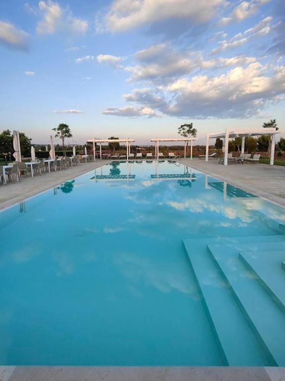 En swimmingpool med klar himmel og en overdækket pavillon.