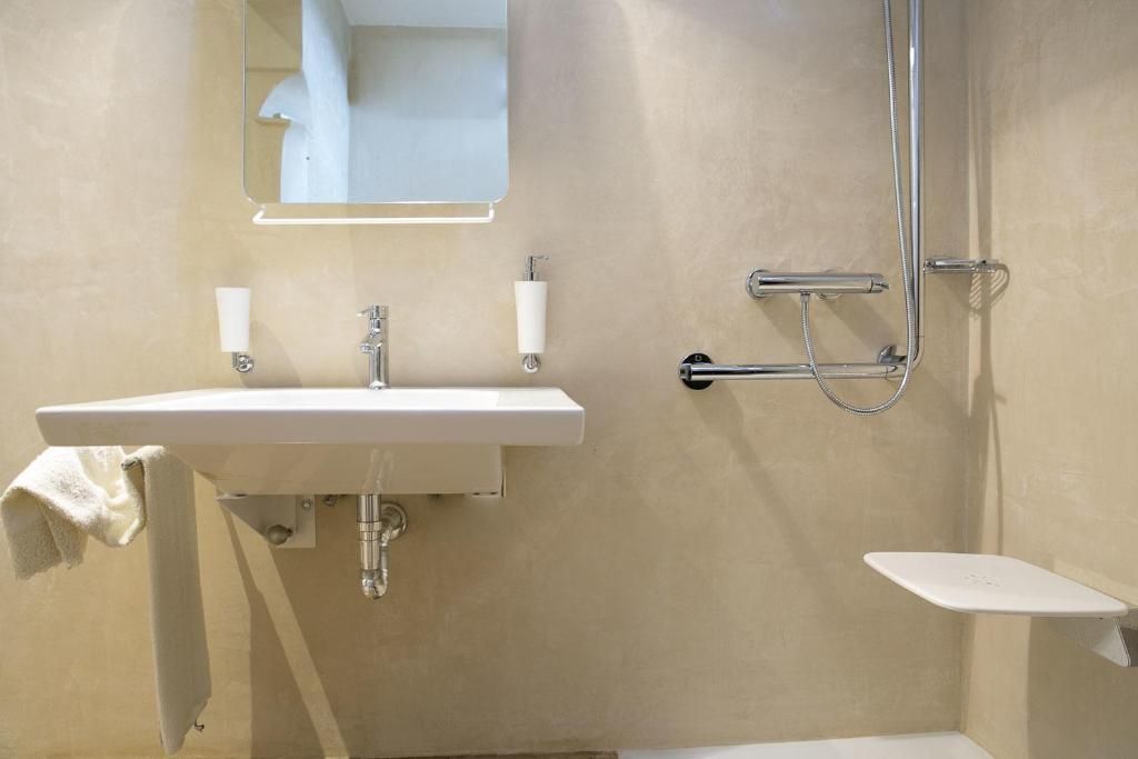 A bathroom with a white sink, a mirror, a towel rack, and a shower area.