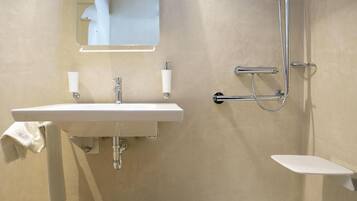 A bathroom with a white sink, a mirror, a towel rack, and a shower area.