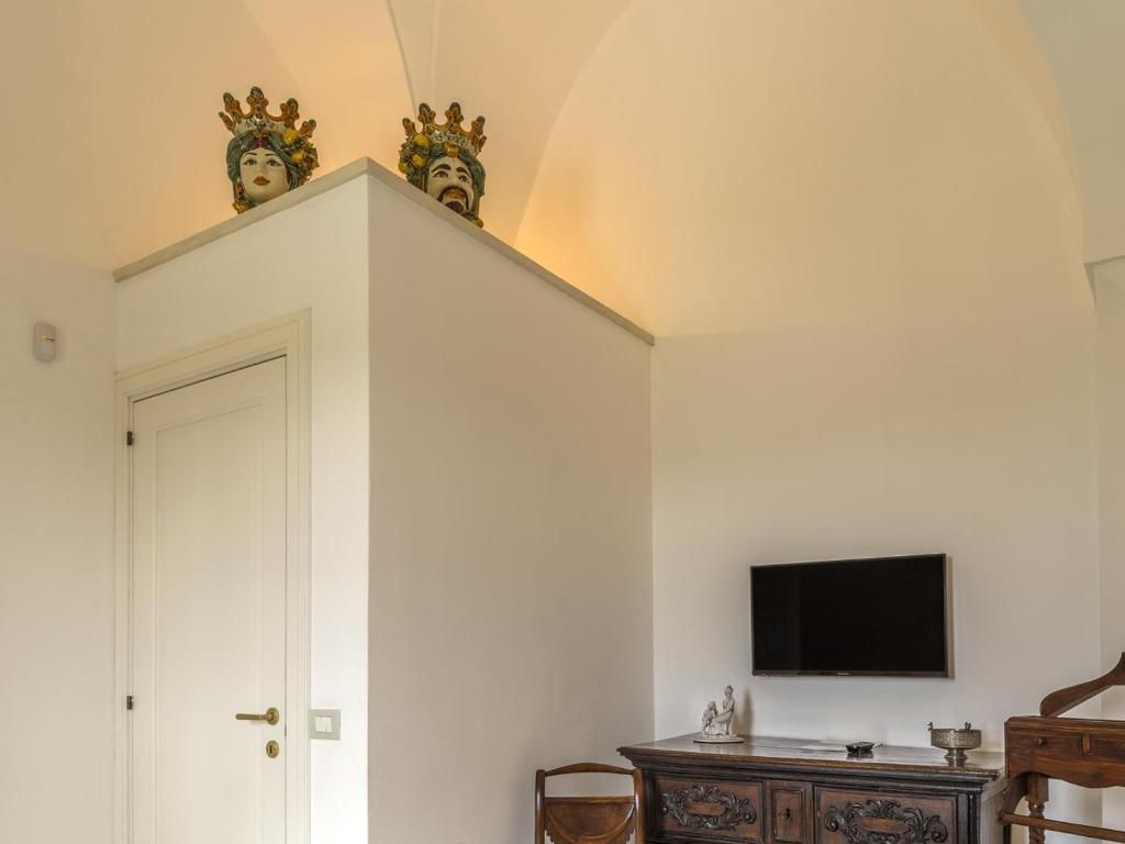A room with a white door, a flat-screen TV mounted on the wall, and a wooden cabinet with decorative carvings.