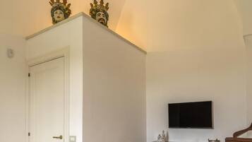 A room with a white door, a flat-screen TV mounted on the wall, and a wooden cabinet with decorative carvings.