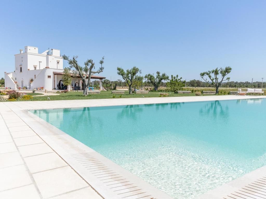 Una piscina con un edificio bianco sullo sfondo.