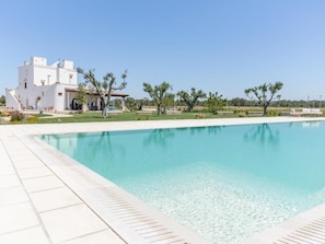Una piscina con un edificio blanco al fondo.