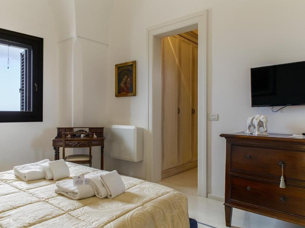 Una habitación de hotel con una cama, un escritorio, una silla, un televisor y un armario.